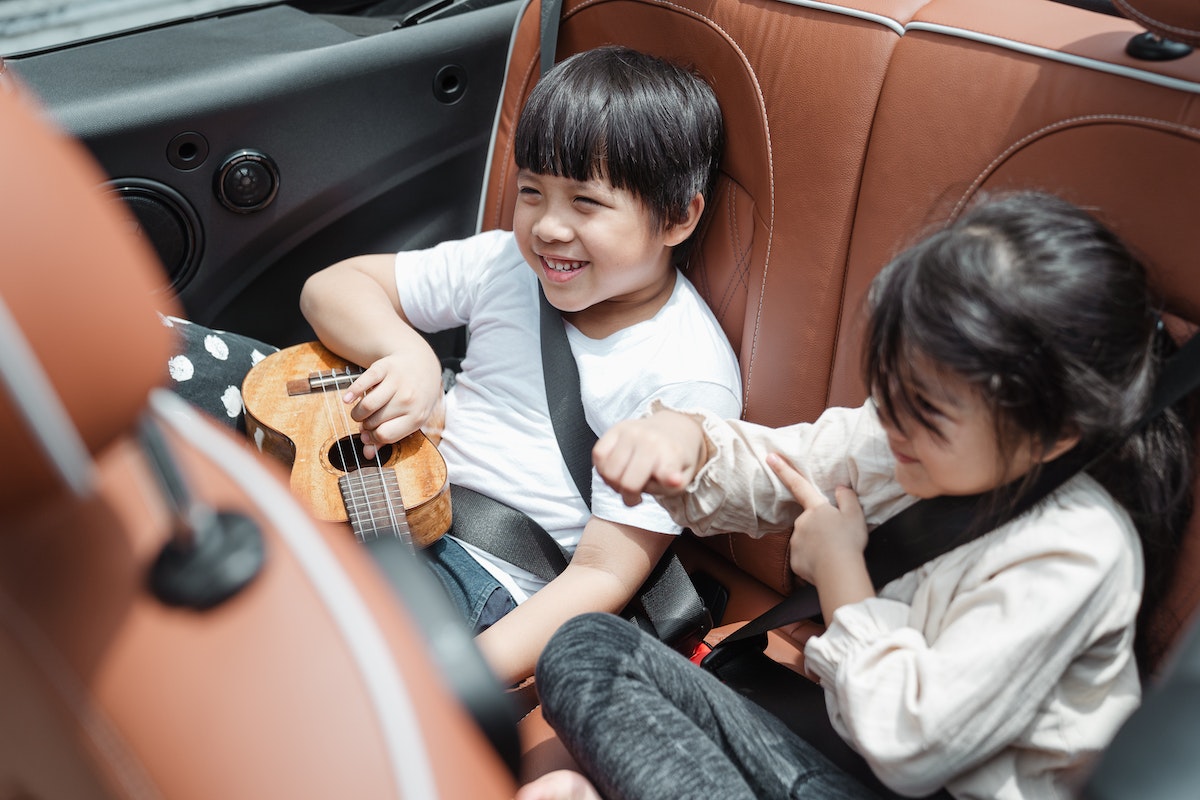 Happy Asian kids traveling in car