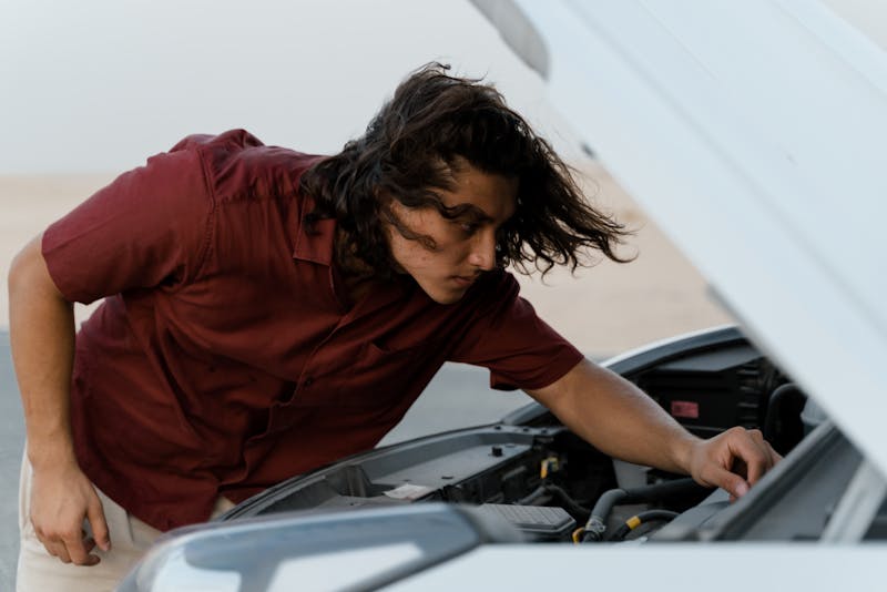 a man looking at his car's hood